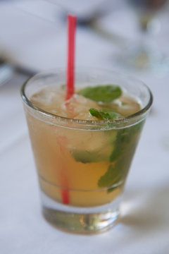 Fancy mint bourbon drink in glass with red straw; vertical image