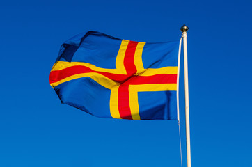 Flag of Aland Islands against the blue sky, national patriotic background