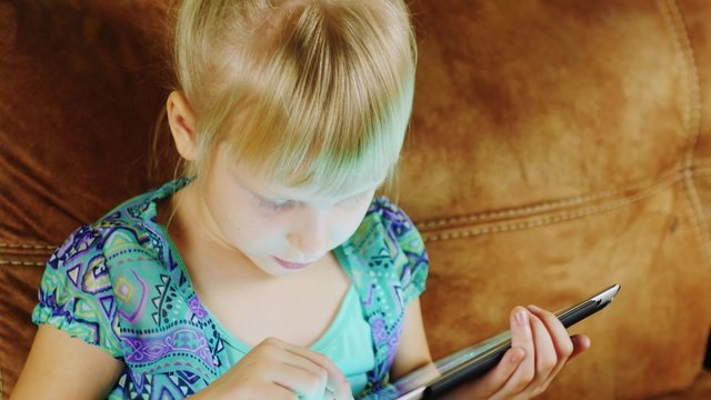 Funny blonde girl playing on the tablet home