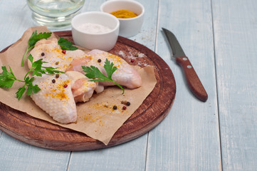 Raw chicken wings with curry seasoning, oil, parsley and pepper