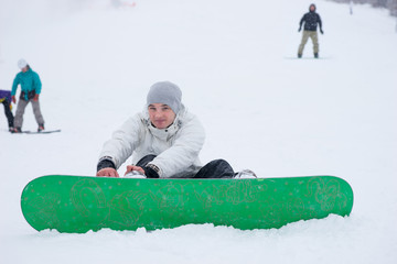 Handsome guy tightening his snowboard in the snow