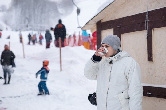 Young man standing drinking coffee at a ski resort