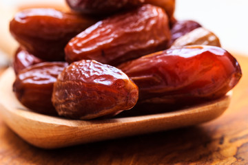 dried dates on spoon wooden background