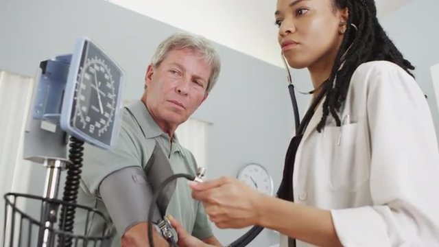 Black woman doctor checking patient's blood pressure