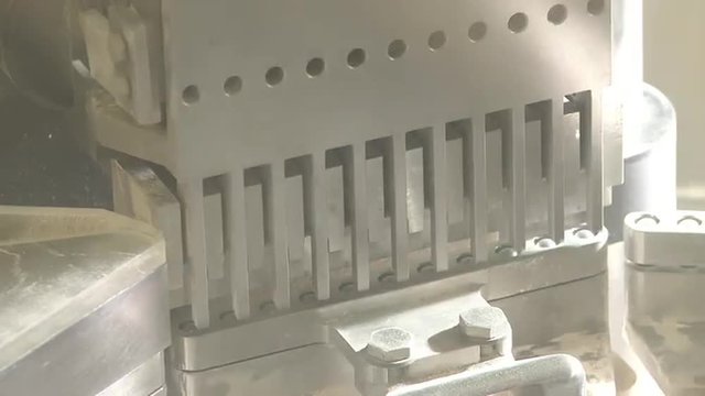 Closeup shot of a metal stamping machine expelling capsules.