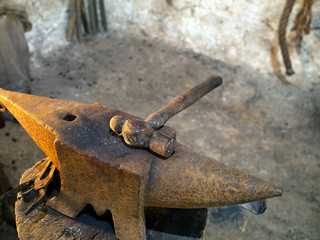 Rusty old hammer and anvil, lit by flame (out of shot)