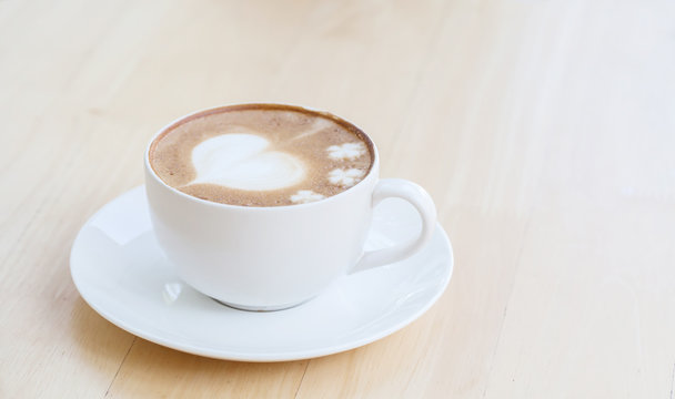 heart symbol on latte coffee cup on table