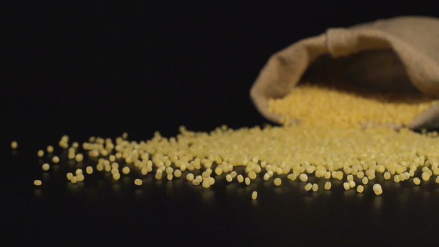 SLOW (240fps): A cloth bag falls on a table and a Couscous scatter out it
