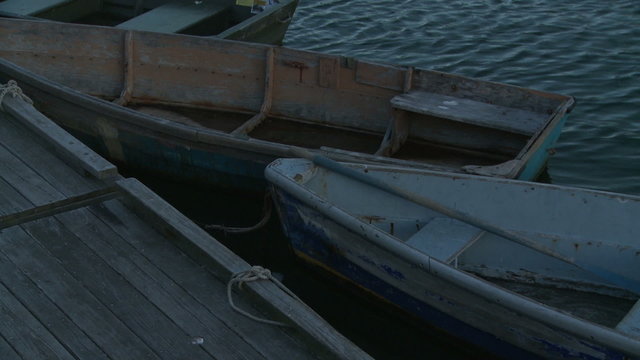 Two old, wooden rowboats tied to a dock.
