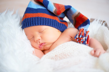 Cute newborn baby in blue knit cap sleeping in basket
