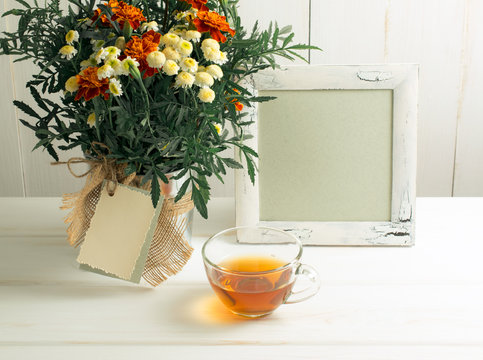 Tagetes flower bouquet with photo frame and cup of tea
