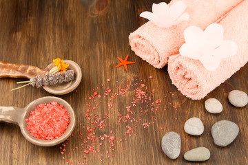Spa composition with towels, sea salt on wooden background. Aromatherapy.