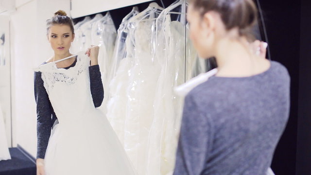 girl with wedding dress flaunts front of the mirror