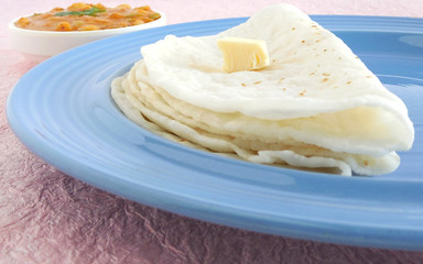 Indian food rice roti or rice flat bread, a traditional, popular and vegetarian dish, is made from rice flour dough. The bread is folded and has a butter dollop as a topping.