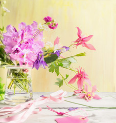 Garden flowers in glass vase on wooden table