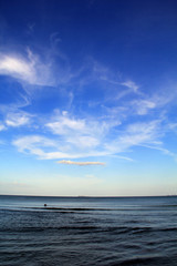cloudy blue sky leaving for horizon above a blue surface of the sea