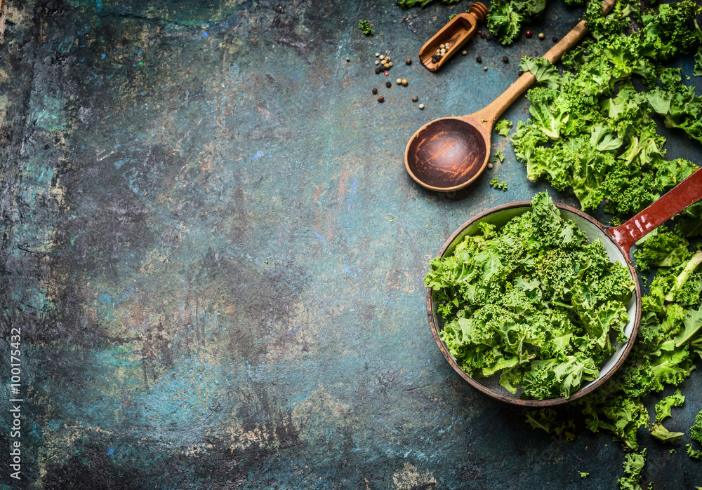 Sticker fresh kale in cooking pot with wooden spoon on rustic background, top view, border. healthy food or 