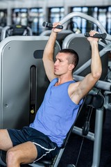 Serious man using exercise machine 