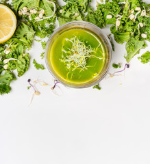 Healthy green smoothie drink in glass with kale and  ingredients on white wooden background, top view. Detox  nutrition and cleaning food concept.