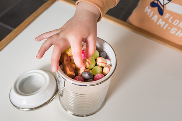 Child picks candy from a jar full of colorful candy
