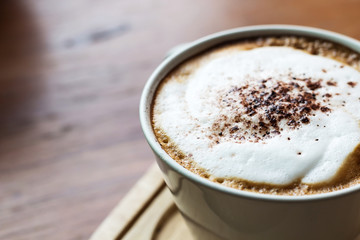 Top view of Cappuccino coffee in a white cup on wooden background.