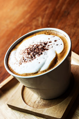 Top view of Cappuccino coffee in a white cup on wooden background.