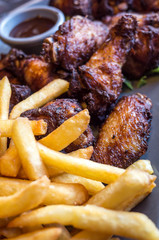 Chicken wings with sauce and golden French fries potatoes
