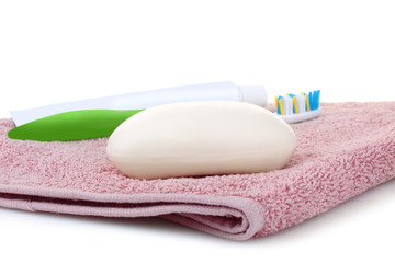 Obraz na płótnie Canvas toothbrush with toothpaste and soap lying on a pink towel isolated on white background