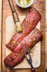 Raw fresh lamb fillet marinating for cooking or BBQ grill with brush and meat fork , top view,...