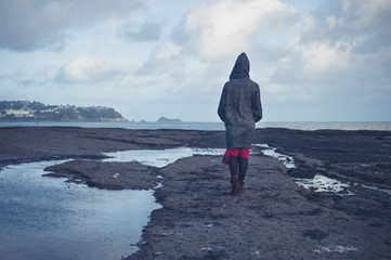 Young woman in hooded coat walking on beach