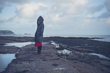 Young woman in hooded coat walking on beach