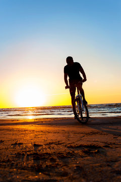 Man cyclist silhouette on blue sky and multicolored sunset backg