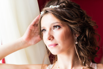 Fototapeta premium Beautiful young bride with wedding makeup and hairstyle in bedroom