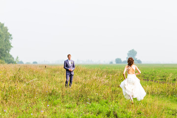happy beautiful bride and groom walking on field 