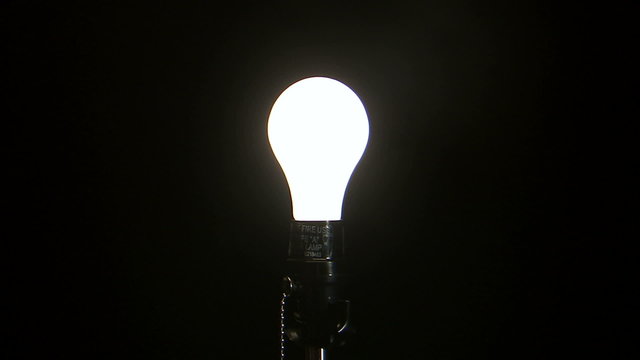 Light bulb turning on against a black background.