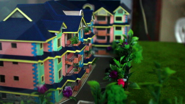 Handheld shot of a miniature scene of houses on display.