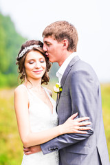 Stylish beautiful happy bride and groom in the meadow