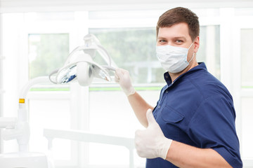 Cheerful young dentist is presenting modern equipment