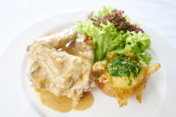 Rabbit in sauce with potato on white plate