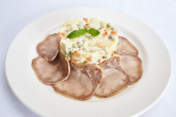 Olivier with beef tongue on white plate studio shot