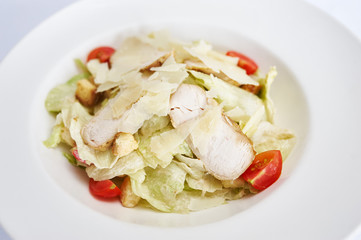 Caesar salad with chicken on white plate studio shot