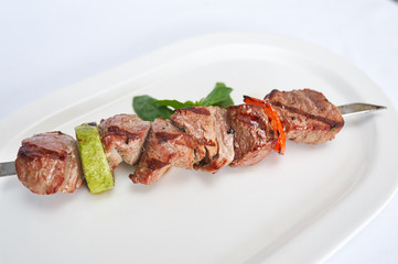 Skewers of beef on white plate studio shot