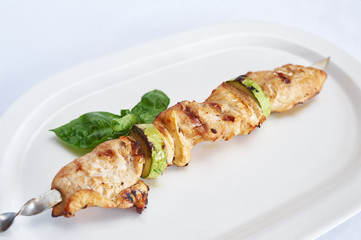Skewers of chicken on white plate studio shot