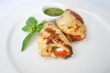 Chicken with pesto on white plate studio shot