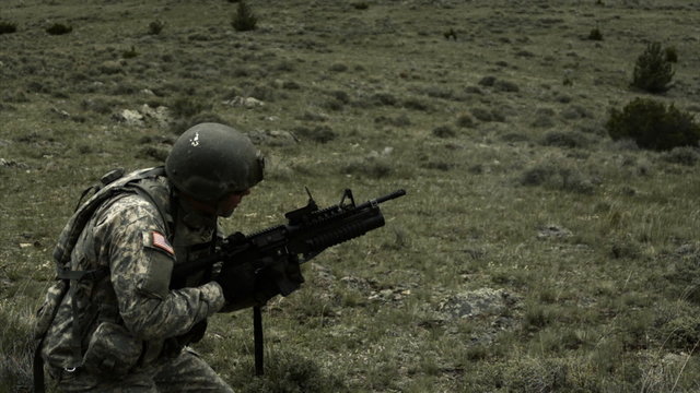 Slow motion clip of soldier firing 40mm grenade launcher while kneeling.