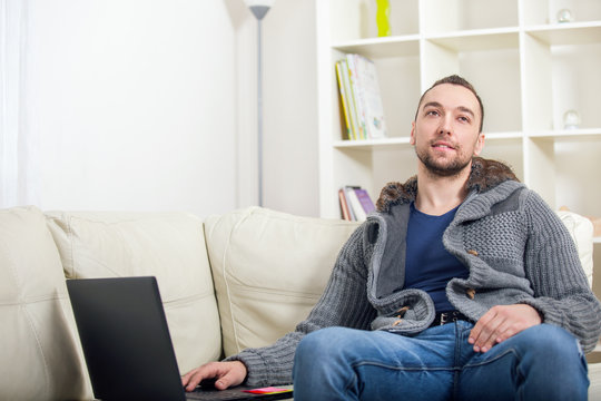 Handsome man sitting on sofa with laptop