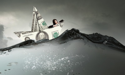 Businesswoman in boat made of dollar banknote