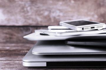 Pile of different modern electronics gadgets on old wooden background