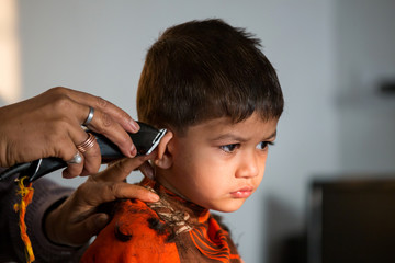 two year old kid having a haircut  with wet eyes after crying early morning with golden light...