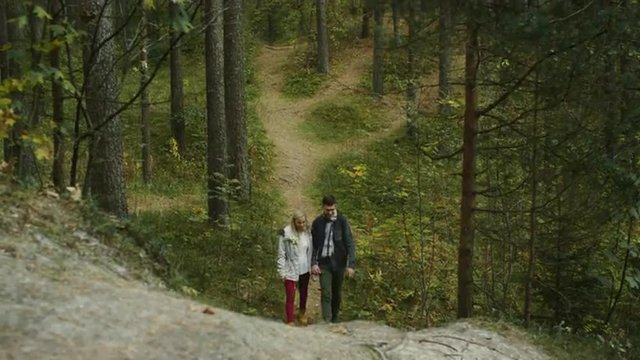 Couple is walking and going uphill in an autumn forest trail. Shot on RED Cinema Camera.